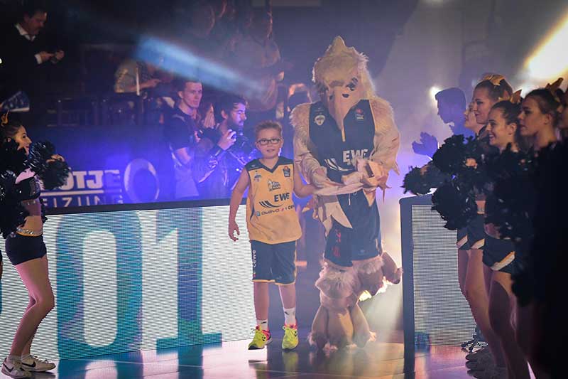 6th Man Caspar läuft mit Hubird bei einem Heimspiel der EWE Baskets Oldenburg ein.