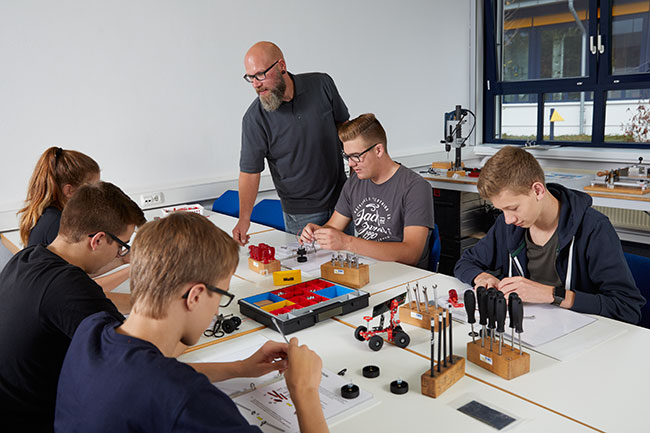 Schüler sitzen an einem Tisch und bauen Modelle zusammen.