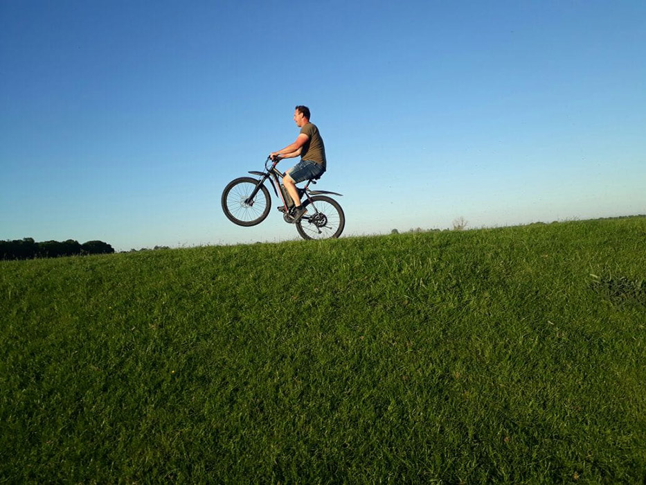 Mann mit E-Bike fährt auf dem Hinterrad