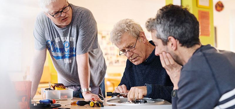 Mehrere Personen reparieren einen Plattenspieler.
